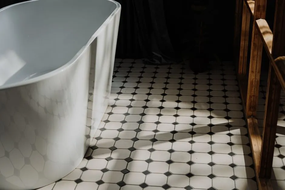 Modern tasarımı sergileyen serbest ayaklı küvet ve şık altıgen yer karolarına sahip minimalist banyo.