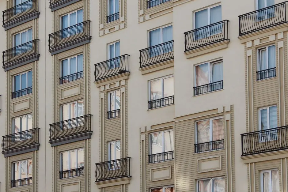 Balkon ve pencereleri olan modern bir konut binasının cephesinin yakın çekimi.