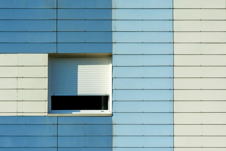 Mavi ve bej cephe üzerinde tek bir pencere kepenği bulunan minimalist mimari detay.
